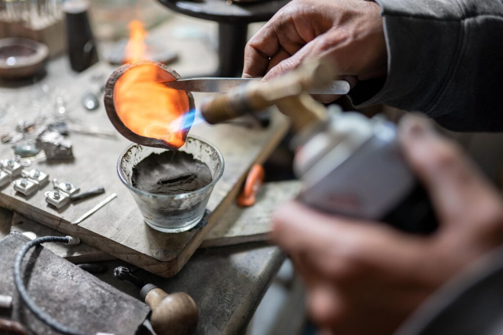 Ein handwerklicher Juwelier gießt geschmolzenes Silber